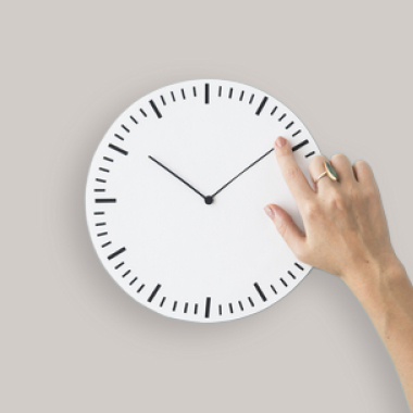 Hand berührt das Zifferblatt einer analogen Uhr