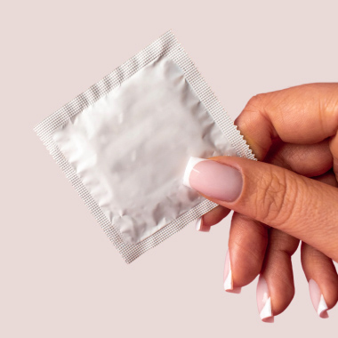 Nahaufnahme einer Frauenhand, die eine Kondomverpackung hält