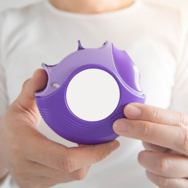 Junger Mann hält einen lilanen Inhalator