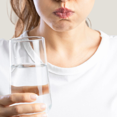 Frau spült Mund mit Wasser aus