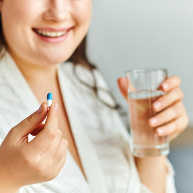 Eine Frau nimmt eine Kapsel mit einem Glas Wasser ein