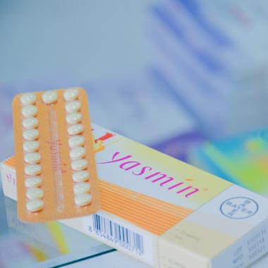 Nahaufnahme einer Frau, die ein Papierdiagramm einer Gebärmutter auf hellrosa Hintergrund hält.