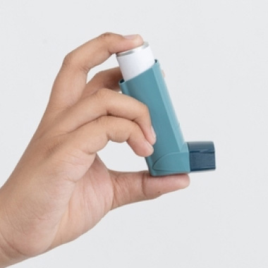 A close-up of a male hand holding an inhaler.