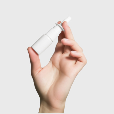 A woman with hay fever symptoms using a nasal spray