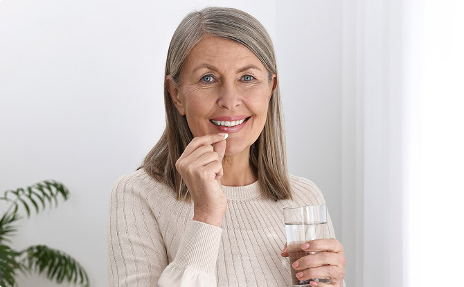 A woman taking a tablet with a glass of water