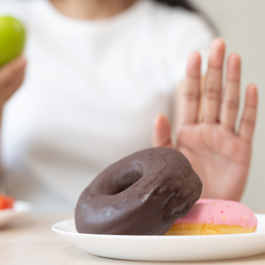 Close-up of a female hand pushing away a plate of unhealthy foods