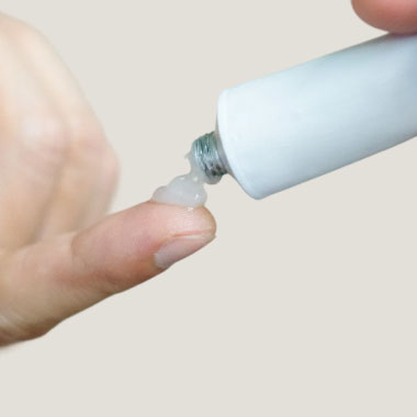 A fingertip with a small amount of cream on it