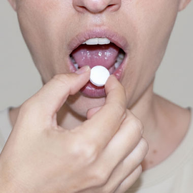 Close-up of a woman placing tablet on her tongue