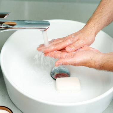 Hands being washed with soap in a sink