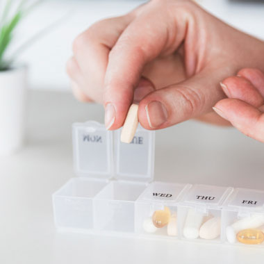 A close-up of hands holding a glucometer and a selection of tablets.