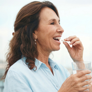 Mature woman holding a tablet and drinking a glass of water