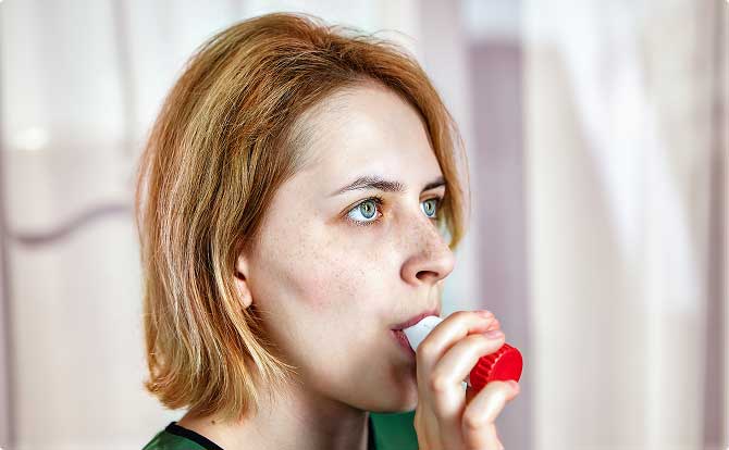 A young woman using an asthma inhaler
