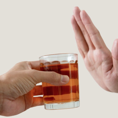 Gros plan d’une femme refusant une boisson alcoolisée offerte par un homme.