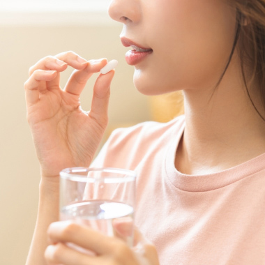 Une femme prenant un comprimé avec un verre d’eau