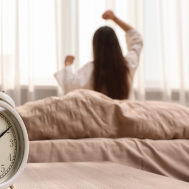 Une femme s’étirant dans son lit en regardant par la fenêtre
