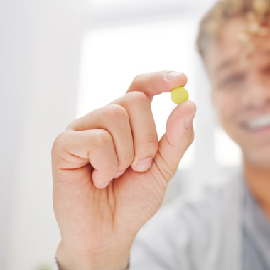 Gros plan d’un homme tenant un comprimé jaune