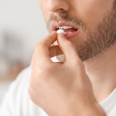 Gros plan d’un homme prenant un comprimé blanc