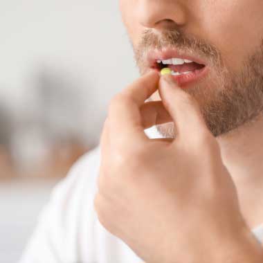 Gros plan d’un homme prenant un comprimé blanc
