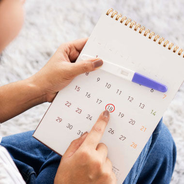 Un test de grossesse posé sur un assortiment de pilules contraceptives et de préservatifs.