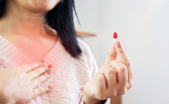 Femme prenant une gélule pour soulager les symptômes du reflux gastro-œsophagien