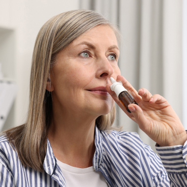 Femme tenant un spray nasal devant son nez