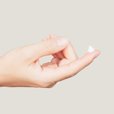 Um plano aproximado de uma gota de creme no dedo de uma mulher.