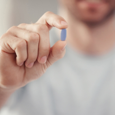 Um homem com um comprimido de Tadalafil na mão