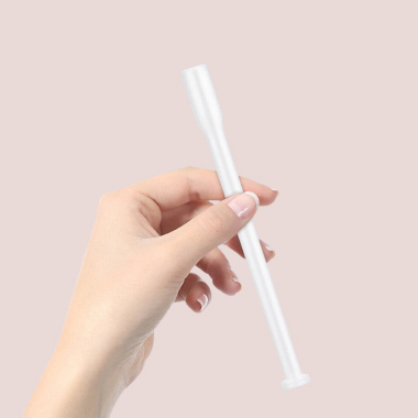 Kvinnas hand som håller en applikator på rosa bakgrund