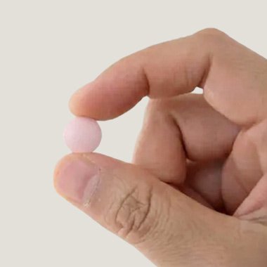 Närbild på en man som håller upp en rosa tablett