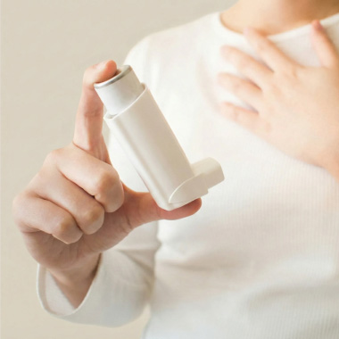 Närbild på en kvinna som använder en inhalator och har astmasymtom.